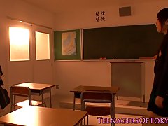 Two Asian schoolgirls are cuddling each other’s nice tits, while in front of the black board